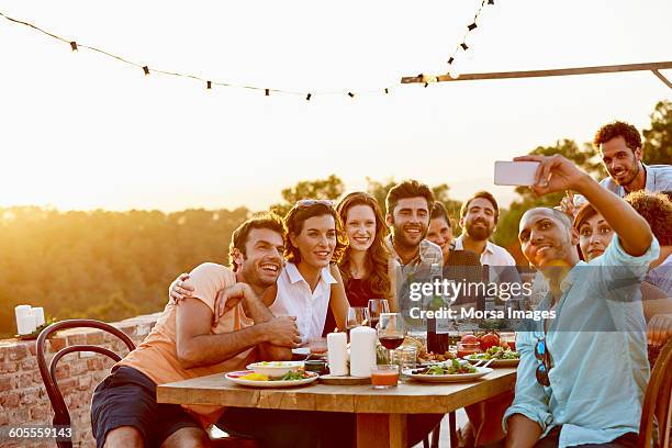 man taking group selfie on mobile phone at party - travel memories stock pictures, royalty-free photos & images