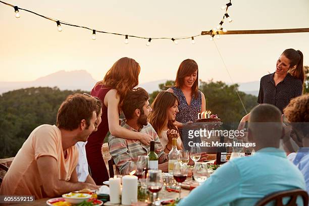 woman carrying cake by friends at table - 20 29 years stock pictures, royalty-free photos & images