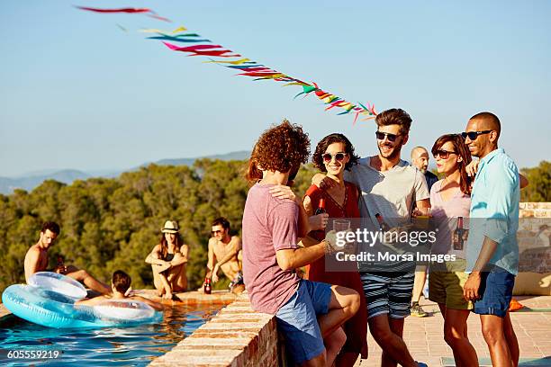 friends enjoying drinks at poolside - man lilo pool photos et images de collection