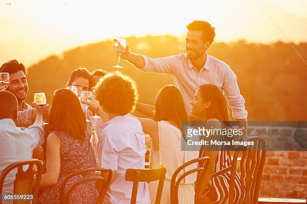 man toasting wineglass with friends at party - evening meal stock pictures, royalty-free photos & images