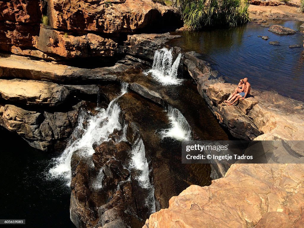 Couple sitting next to a waterfall