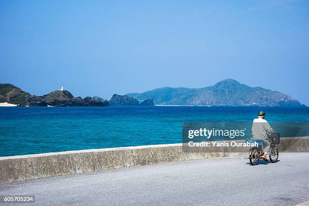 man on a bicycle in zamami island with beautiful beach in okinawa islands, ryukyu, japan - archipelago stock pictures, royalty-free photos & images