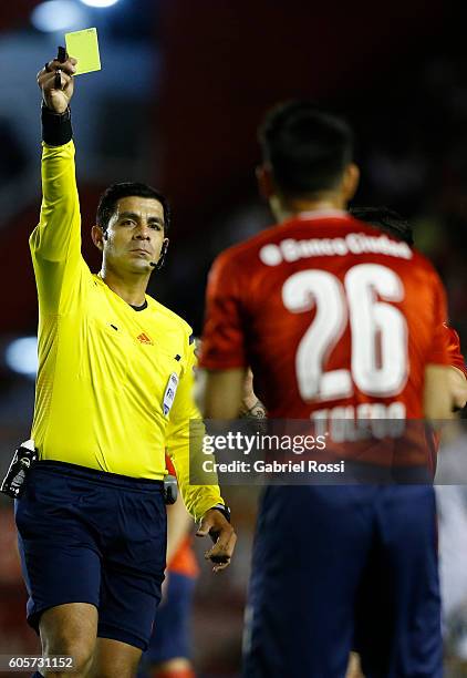 Referee Enrique Caceres shows a yellow card to Gustavo Toledo of Independiente during a match between Independiente and Lanus as part of Copa...
