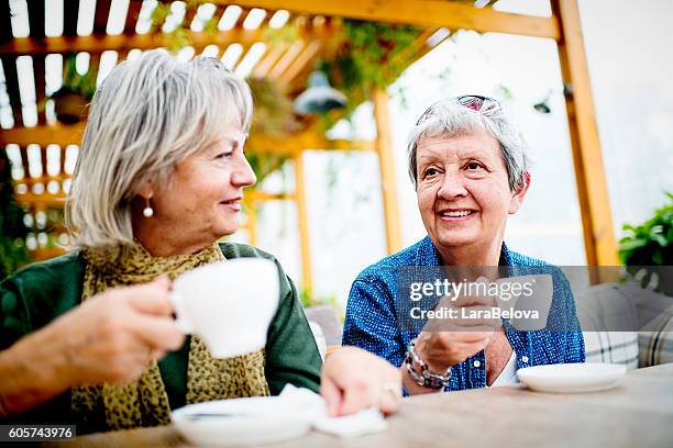 due donne nel caffè sul marciapiede - solo donne mature foto e immagini stock