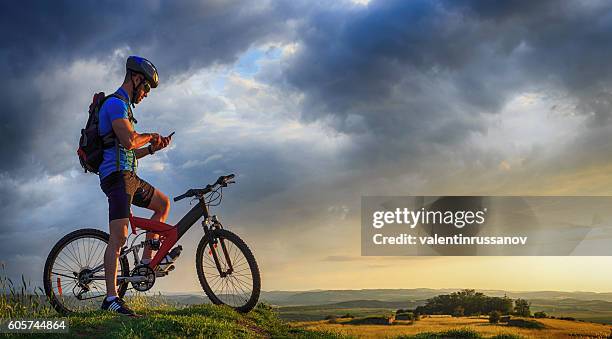 mountainbiker che utilizza il cellulare in cima alla montagna - extreme foto e immagini stock