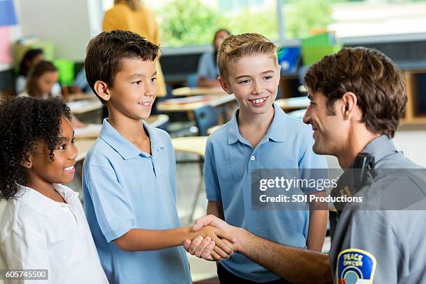 happy police officer greets schoolchildren - friendly police stock pictures, royalty-free photos & images