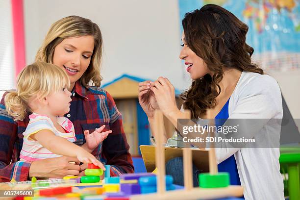 lehrer arbeitet mit vorschulkind sitzen auf dem schoß der mutter - kindergartengebäude stock-fotos und bilder