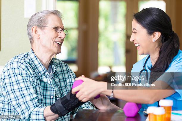 nurse helps senior man with hand weights - sprain stock pictures, royalty-free photos & images