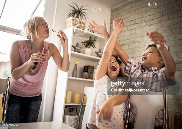 mother and child blowing bubbles - catching bubbles stock pictures, royalty-free photos & images