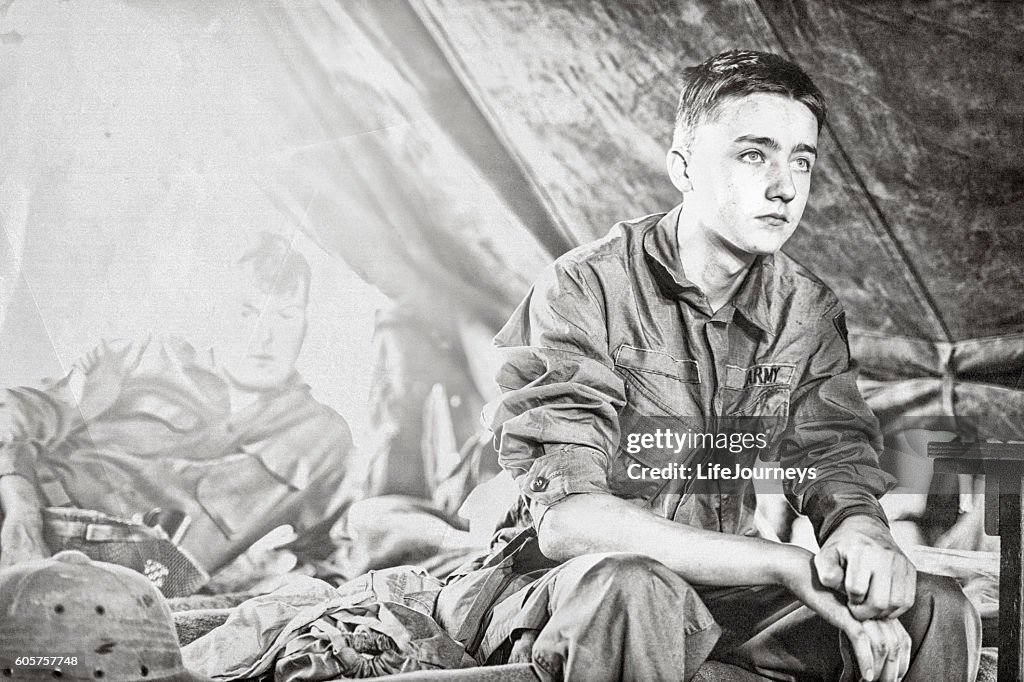 Junger Infanterist aus dem Zweiten Weltkrieg sitzt auf einem Kinderbett in seinem Zelt