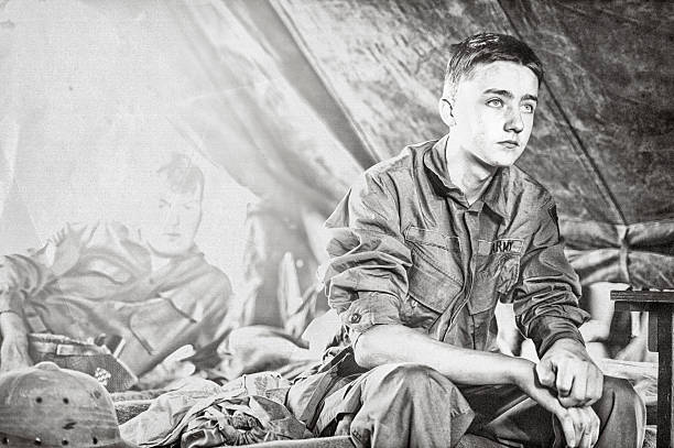 joven soldado de infantería de la segunda guerra mundial sentado en una cuna en su tienda de campaña - segunda guerra mundial fotografías e imágenes de stock