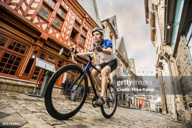 caucasian man cycling on cobblestone street - kassei stockfoto's en -beelden