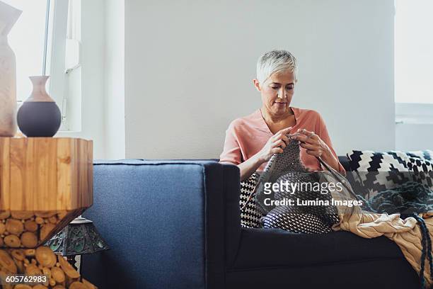 older caucasian woman knitting on sofa - 用針織 個照片及圖片檔