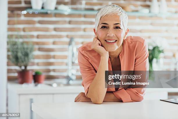 older caucasian woman smiling in kitchen - older woman short hair stock pictures, royalty-free photos & images