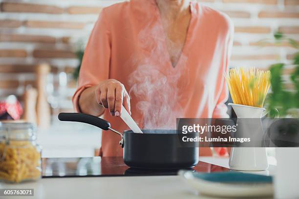 older caucasian woman cooking in kitchen - one pot pasta stock-fotos und bilder