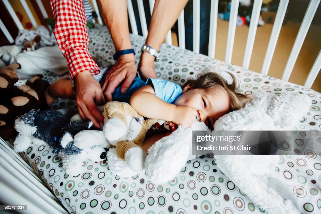 Gay fathers tickling baby son in crib
