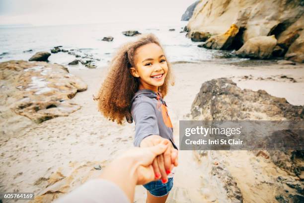 girl pulling hand of mother on beach - mother daughter holding hands stock pictures, royalty-free photos & images