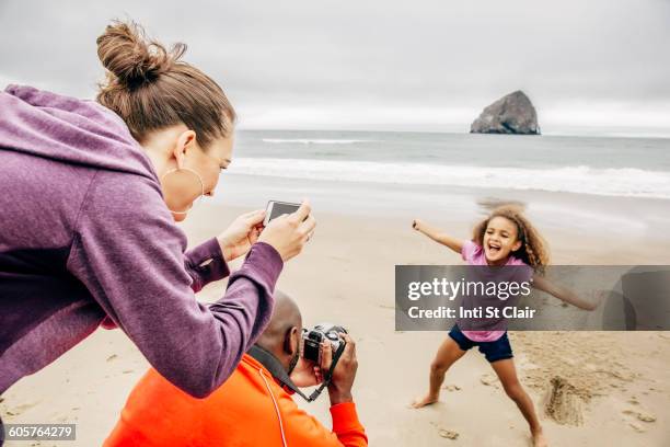 parents photographing daughter on beach - african girls on beach stockfoto's en -beelden