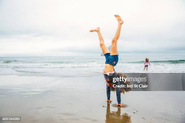 mixed race girl doing handstand on beach - handstand beach stock pictures, royalty-free photos & images