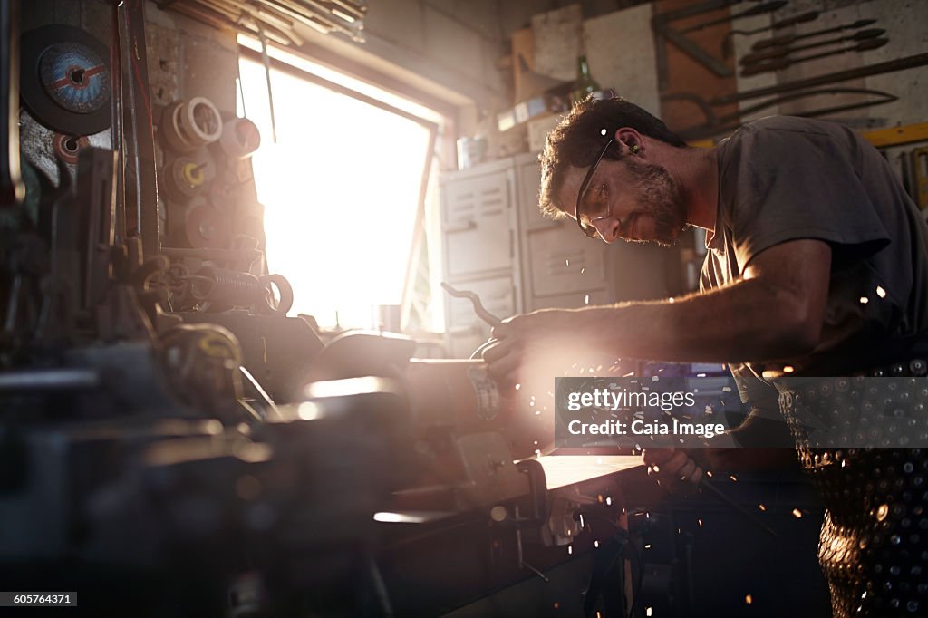 Blacksmith using sander in forge