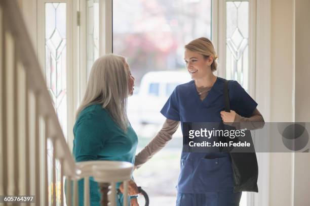 nurse talking to patient in front door - home front stockfoto's en -beelden