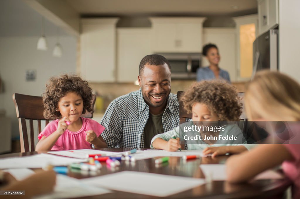 Father and children drawing in kitchen