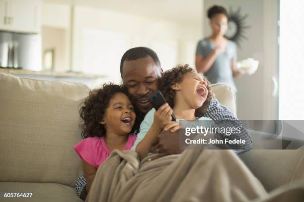 father and daughters playing on sofa - black and white tv stock-fotos und bilder