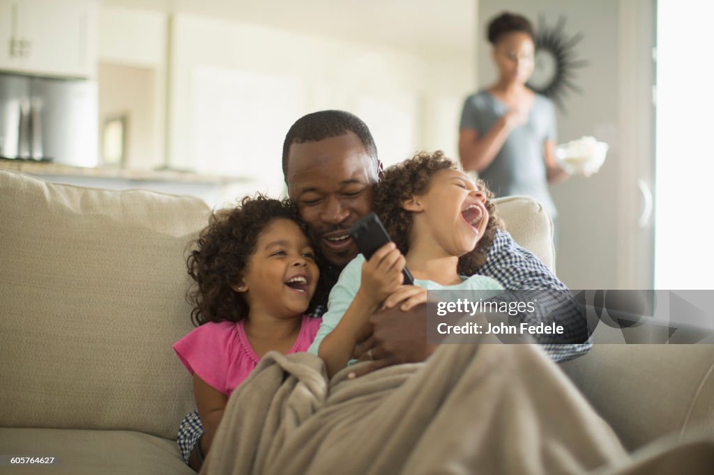 Father and daughters playing on sofa