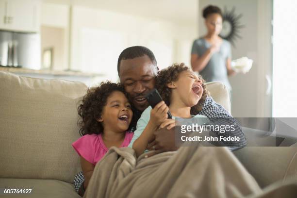 father and daughters playing on sofa - two parents stock pictures, royalty-free photos & images