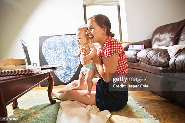 caucasian mother and baby daughter using laptop in living room - voip stock-fotos und bilder