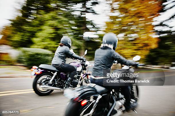 two women riding motorcycles together down road - panorering bildbanksfoton och bilder