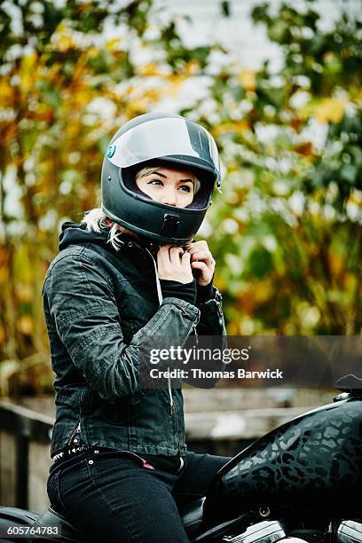 woman adjusting strap on helmet before ride - crash helmet stock pictures, royalty-free photos & images