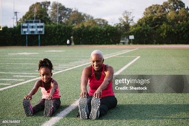 grandmother and granddaughter stretching on football field - 3 generations sport stock pictures, royalty-free photos & images