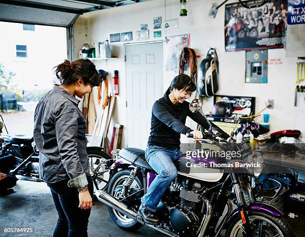 woman sitting on friends motorcycle in garage - woman motorcycle stock pictures, royalty-free photos & images