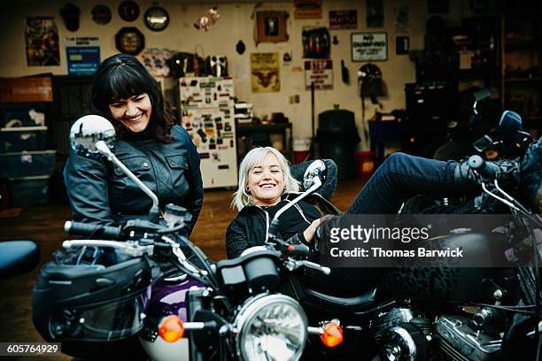 two smiling women relaxing on motorcycles - leanincollection stock pictures, royalty-free photos & images