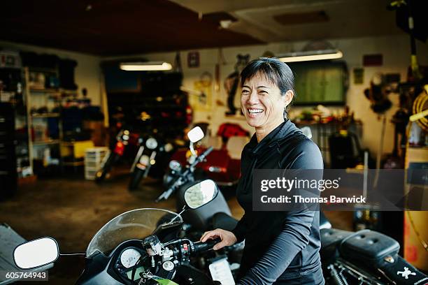 smiling woman with motorcycle in garage - adultes moto photos et images de collection