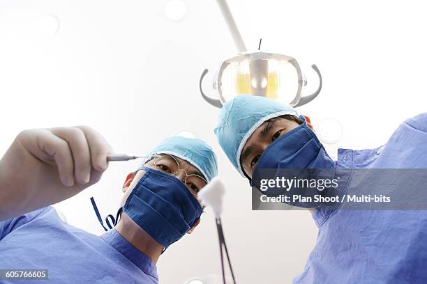 dentist and dental assistant holding extraction forceps, portrait, upward view - extraction forceps stockfoto's en -beelden