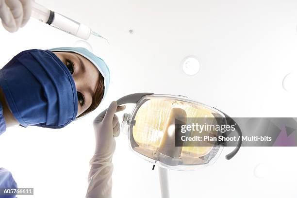 dental assistant holding surgical lamp and syringe, portrait, upward view - extraction forceps stockfoto's en -beelden