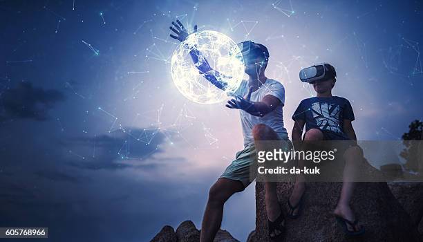 father and son using virtual reality glasses sitting outside - virtual vacations stock pictures, royalty-free photos & images