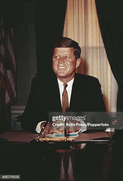 Portrait of President of the United States, John Fitzgerald Kennedy seated behind the Oval Office desk in the White House in Washington DC circa 1961.