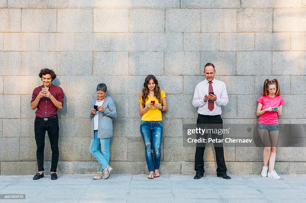 Mixed age range og people texting in a row