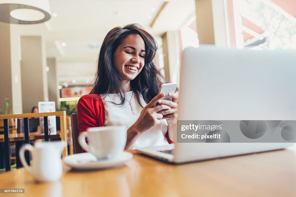 Girl with smart phone and laptop in cafe