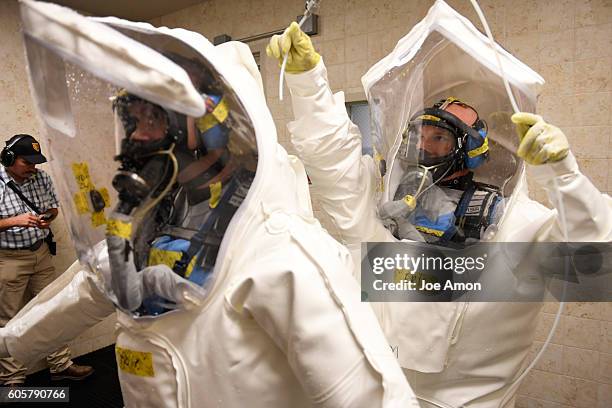 Instrumentation technician Philip Kell is checked by his partner Eric Irvin with a miniaturized continuos air monitoring system after they wash down...