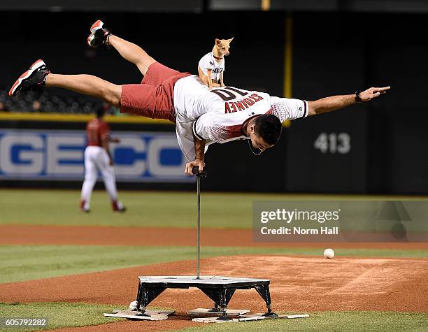 Christian Stoinev and Scooby show off their balancing skills just prior to throwing out a ceremonial first pitch prior to a game between the Arizona...