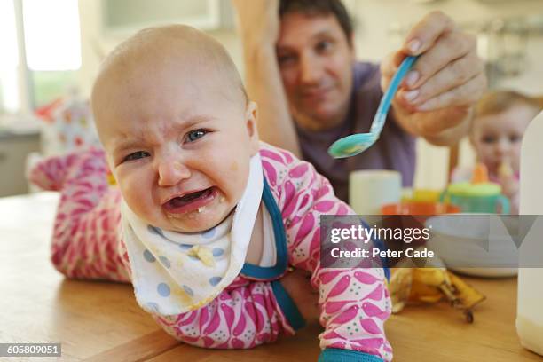 stressed man trying to feed babies, one on table - stress eating stock pictures, royalty-free photos & images