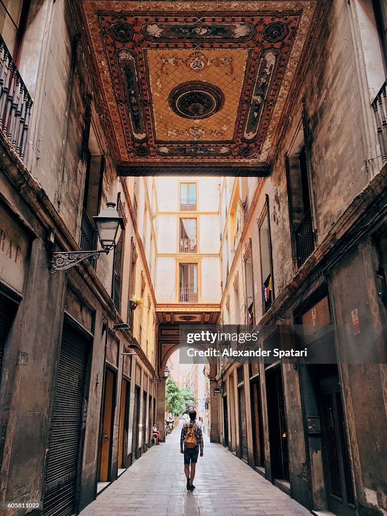 Tourist with backpack bag wandering through the narrow street of Gothic Quarter in Barcelona, Catalonia, Spain