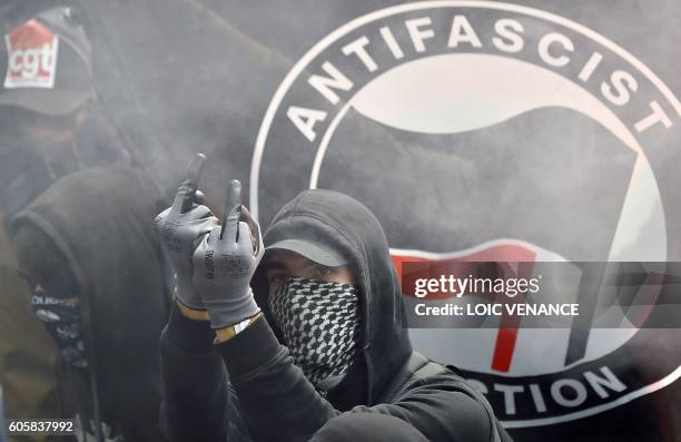 Demonstrator gestures in front of an Antifascist Action flag during a demonstration against the controversial labour reforms of the French government...