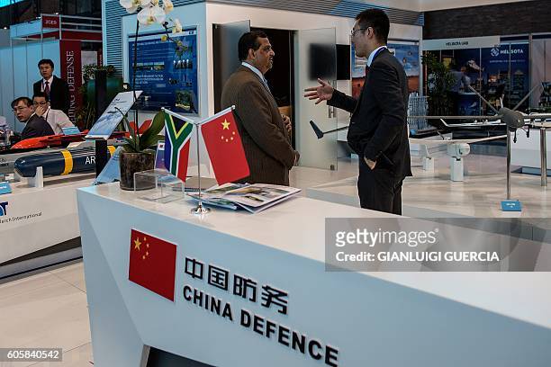 Delegates converse at weaponry and military aviation Chinese Defence stand at the Africa Aerospace and Defence 2016 fair at the South African Air...