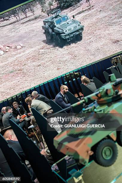 Delegates speak at a weaponry and military aviation stand stand at the Africa Aerospace and Defence 2016 fair at the South African Air Force...