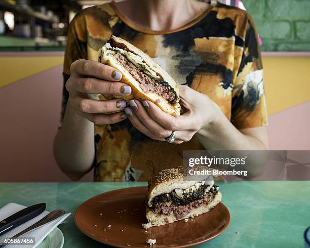 Woman displays a Green Chili Cheeseburger for a photograph at Mission Cantina restaurant in New York, U.S., on Tuesday, April 19, 2016. Top chefs...